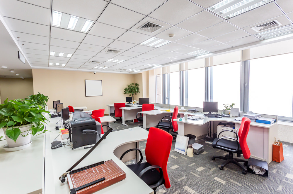 work area in office with desks and red chairs